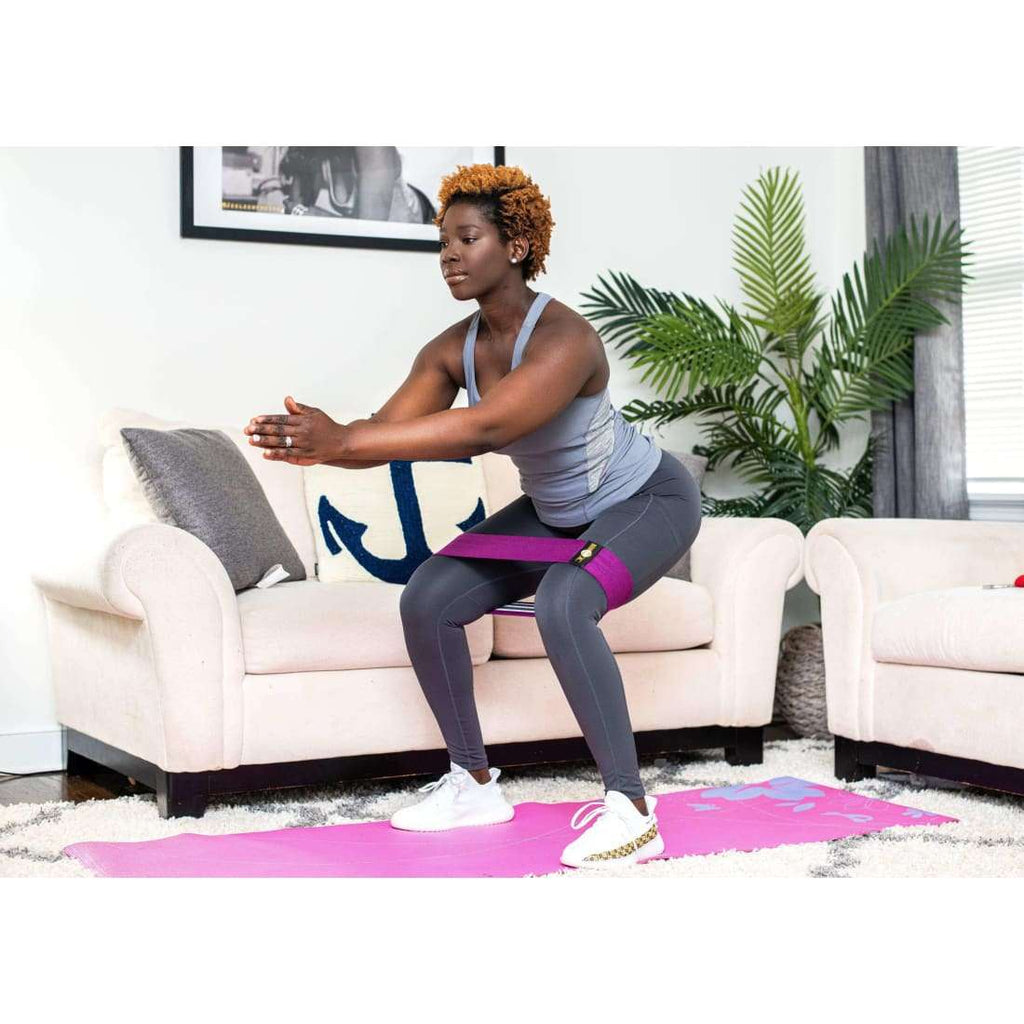 Woman using loop resistance bands for glutes at home on couch